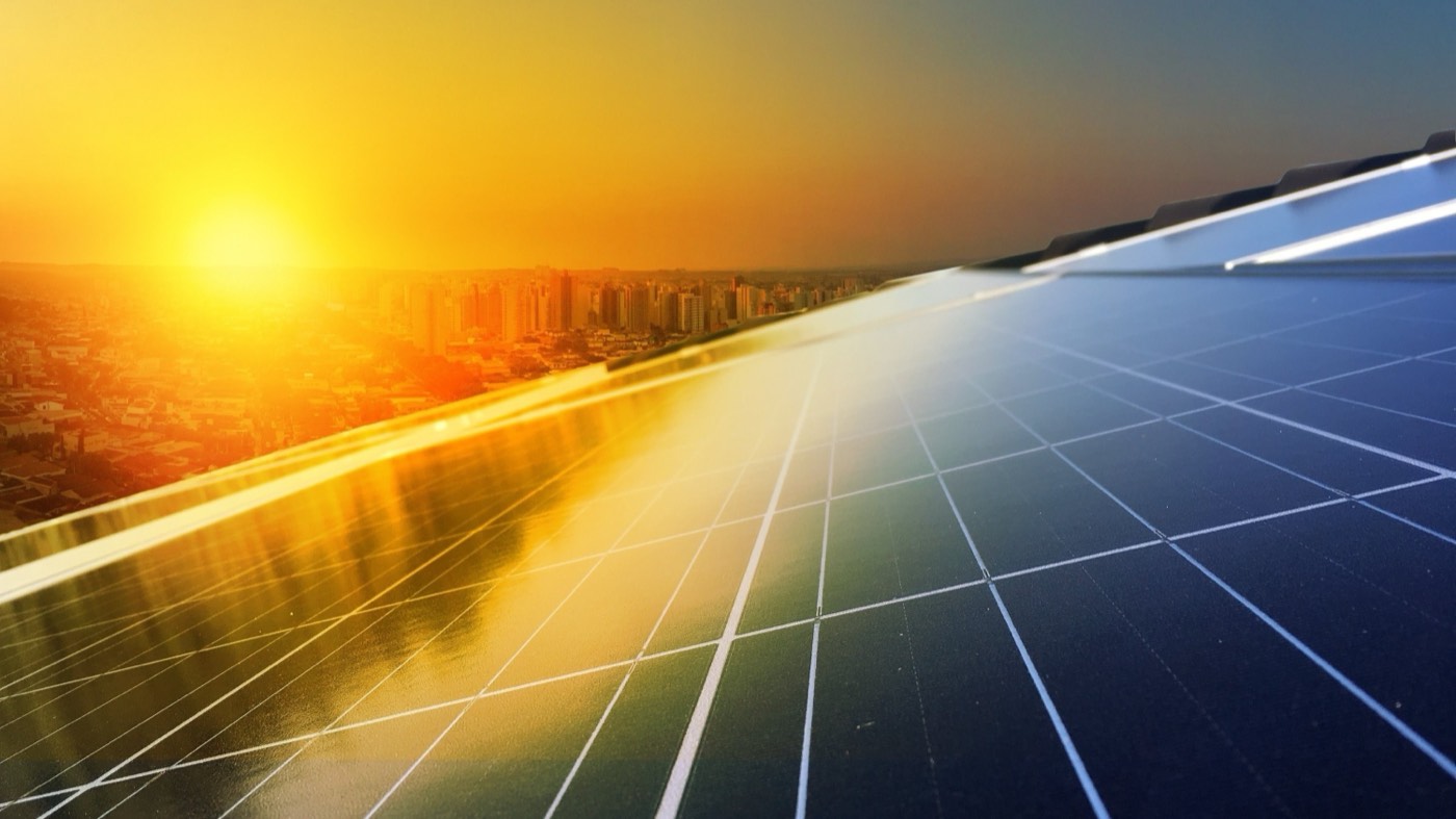 Rooftop solar panels at sunset over a city skyline